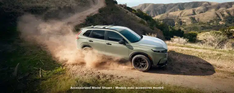 SUV driving on a dirt road in a scenic hilly landscape, creating dust clouds.