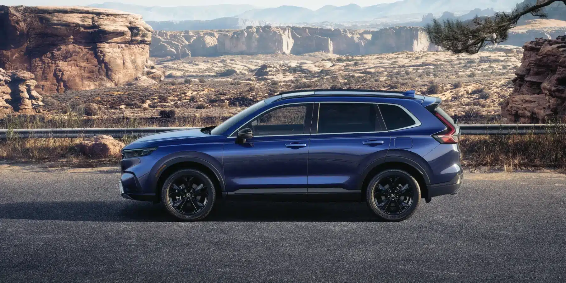 Blue SUV parked on a scenic desert road with rocky formations in the background.