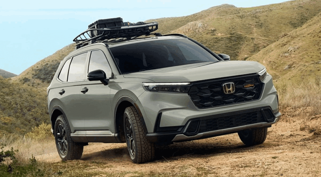 SUV parked on a dirt trail in a hilly landscape, equipped with a roof rack and off-road tires.