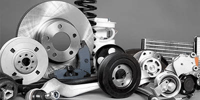 Assorted automotive parts including brake discs, shock absorbers, and pulleys on a gray background.