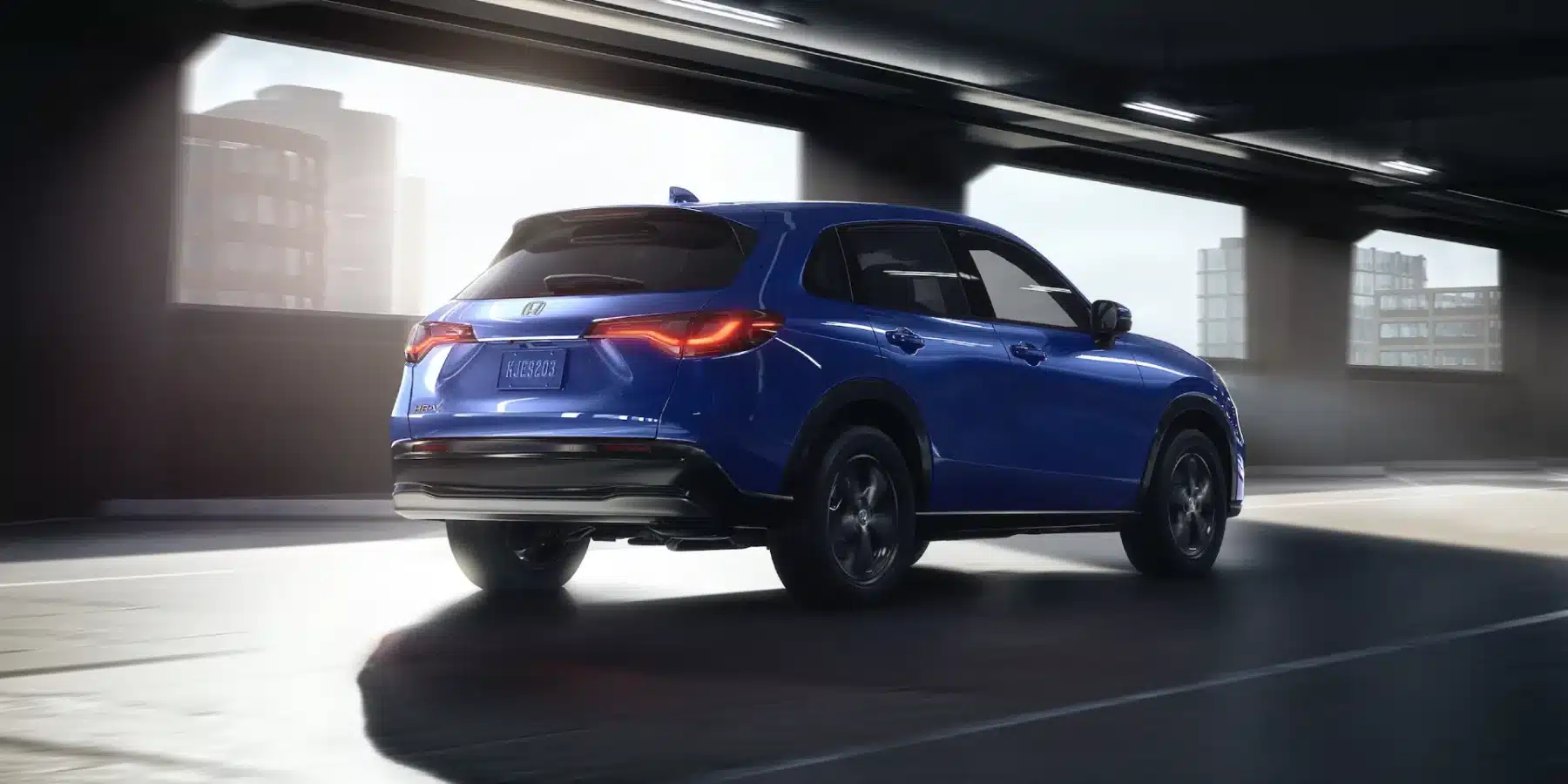 Blue SUV driving in a sunlit urban tunnel, showcasing sleek design and vibrant color.